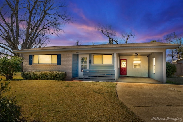 ranch-style house with a yard, brick siding, and concrete driveway