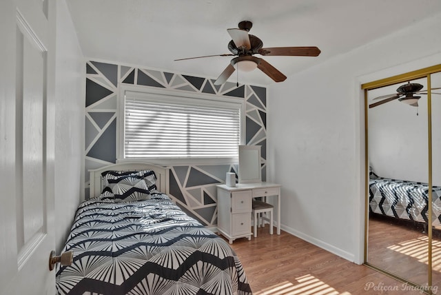 bedroom with ceiling fan, light wood finished floors, a closet, and baseboards