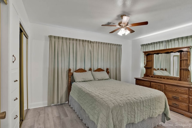 bedroom with light wood-style floors, ceiling fan, visible vents, and a closet