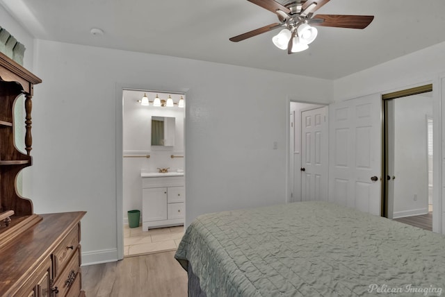 bedroom featuring a closet, light wood-style floors, ceiling fan, ensuite bath, and baseboards