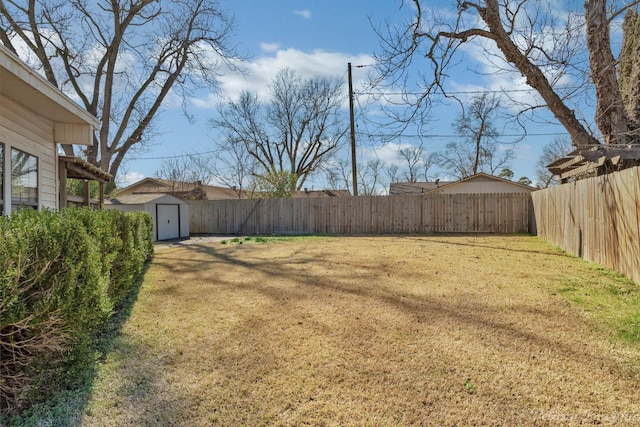 view of yard with a shed, a fenced backyard, and an outbuilding