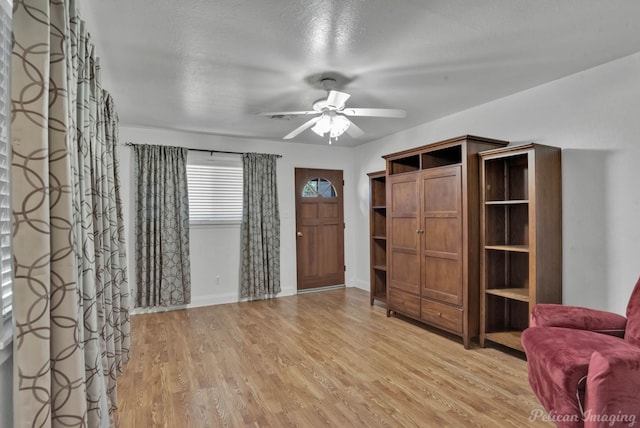 foyer entrance featuring light wood-type flooring, a ceiling fan, and baseboards