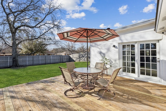 wooden terrace featuring a yard, outdoor dining space, a fenced backyard, and french doors