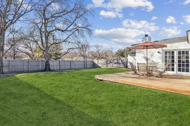 view of yard with french doors, a fenced backyard, a wooden deck, and outdoor dining area