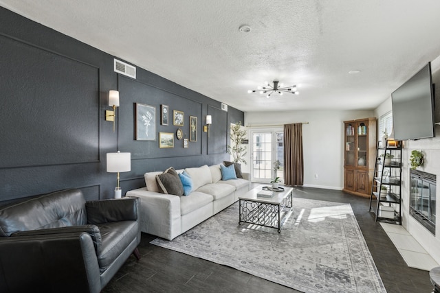 living room with an inviting chandelier, baseboards, visible vents, and a textured ceiling