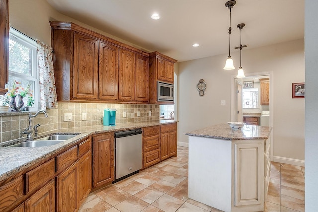 kitchen with a center island, backsplash, appliances with stainless steel finishes, brown cabinetry, and a sink