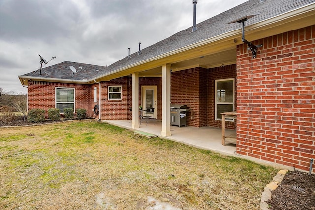 back of house featuring a yard, brick siding, and a patio