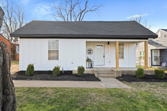 bungalow-style home with a porch, board and batten siding, a shingled roof, and a front yard