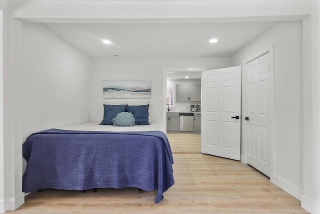 bedroom with ensuite bathroom, light wood finished floors, baseboards, and recessed lighting