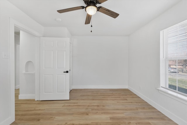 empty room with light wood finished floors, baseboards, and a ceiling fan