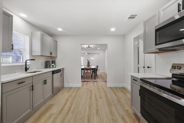 kitchen with visible vents, appliances with stainless steel finishes, gray cabinetry, light wood-type flooring, and a sink