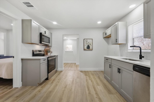 kitchen with visible vents, appliances with stainless steel finishes, a sink, gray cabinets, and a wealth of natural light