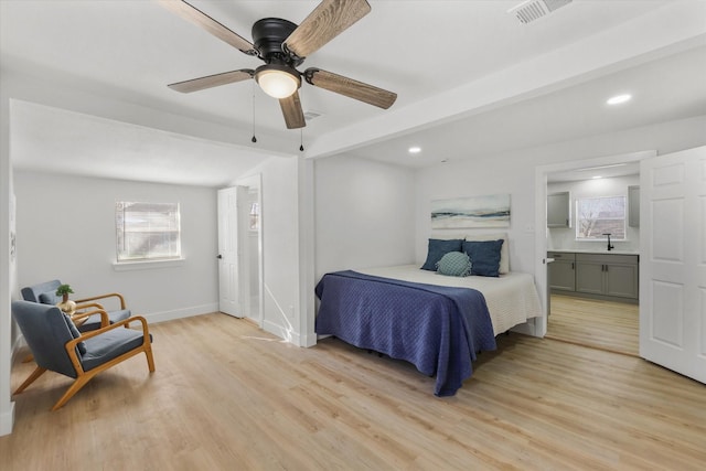 bedroom featuring light wood-style floors, visible vents, a sink, and baseboards