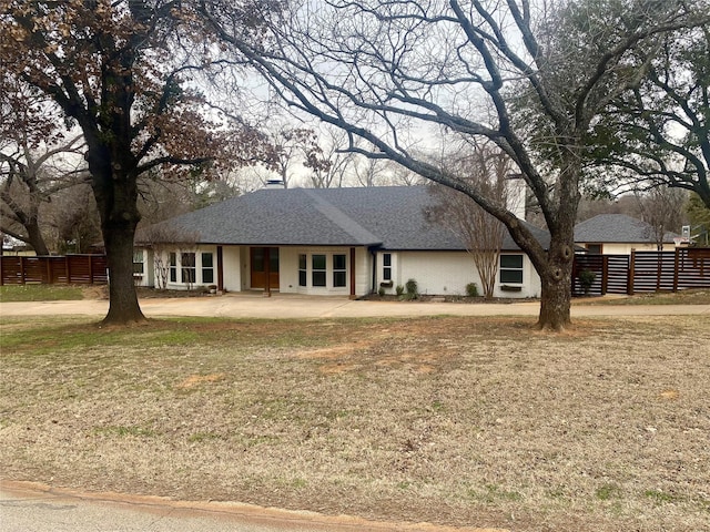 ranch-style house with a patio, brick siding, roof with shingles, and fence