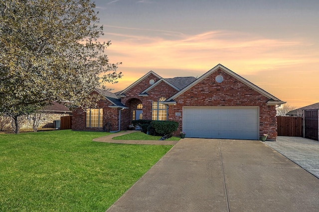 view of front of house with an attached garage, brick siding, fence, concrete driveway, and a front yard