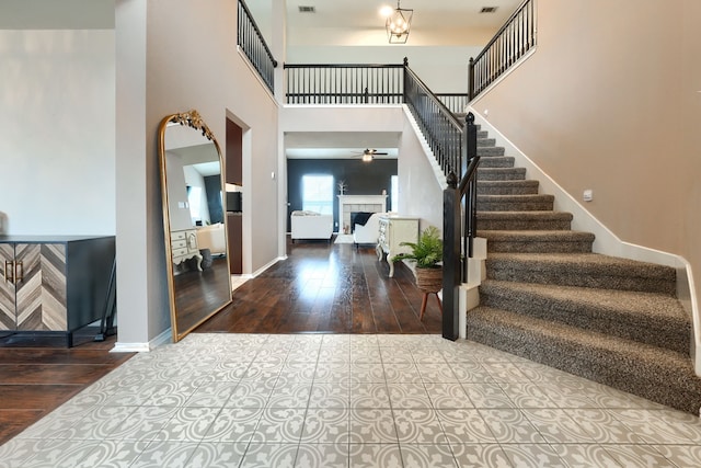 foyer with a high ceiling, a fireplace, baseboards, and wood finished floors