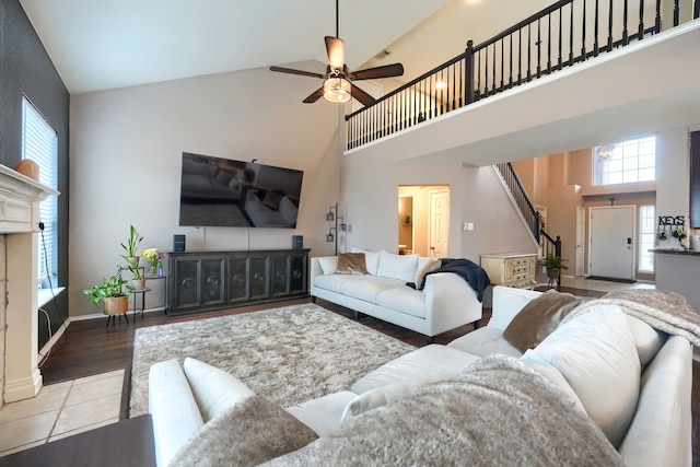 living area featuring stairway, baseboards, high vaulted ceiling, and ceiling fan