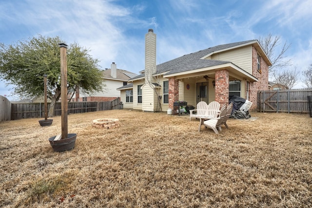 rear view of house with a fire pit, ceiling fan, a lawn, and a fenced backyard