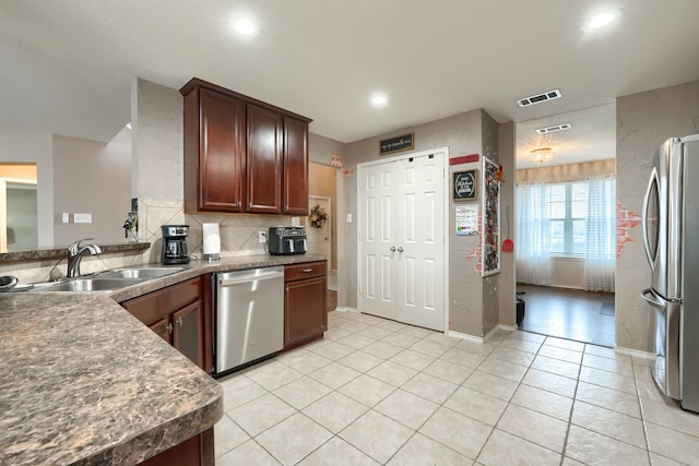 kitchen with light tile patterned floors, a sink, visible vents, appliances with stainless steel finishes, and backsplash