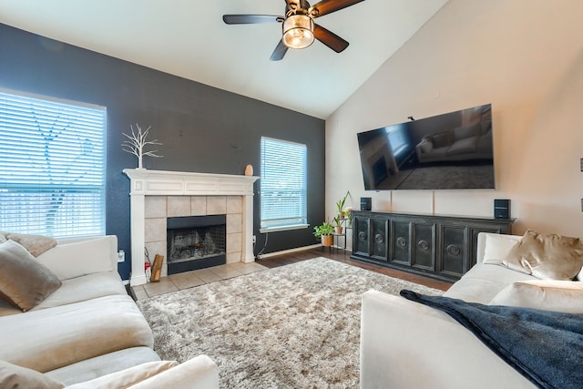 living area with a tiled fireplace, vaulted ceiling, ceiling fan, baseboards, and tile patterned floors