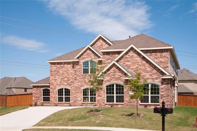 view of front of house featuring a front yard, brick siding, and fence