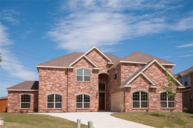 view of front of home with driveway, brick siding, a shingled roof, and a front yard