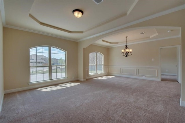 carpeted spare room with arched walkways, a tray ceiling, and ornamental molding