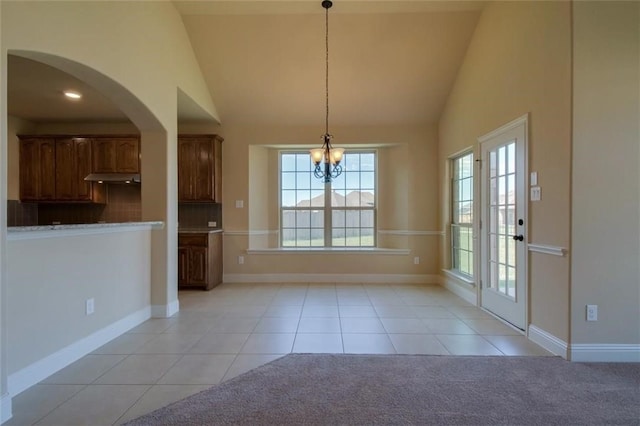 unfurnished dining area featuring a chandelier, light carpet, high vaulted ceiling, and light tile patterned floors