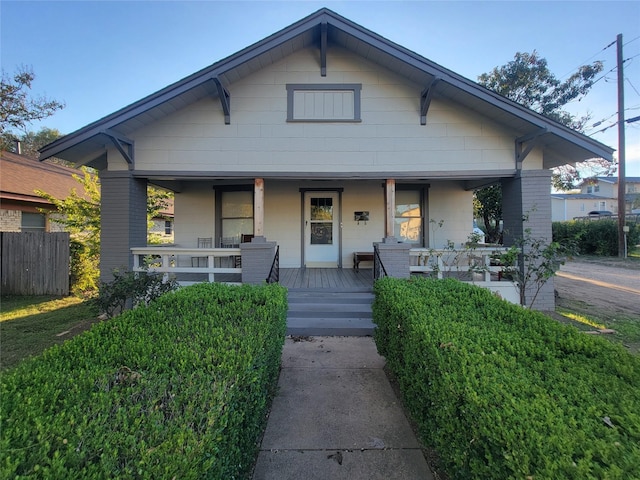 bungalow-style home featuring covered porch and fence