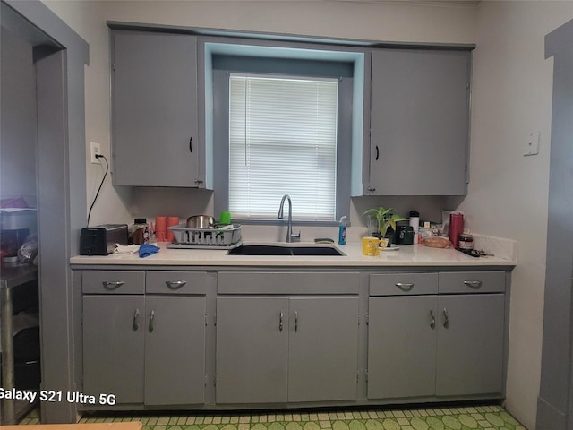 kitchen featuring gray cabinetry, light countertops, and a sink