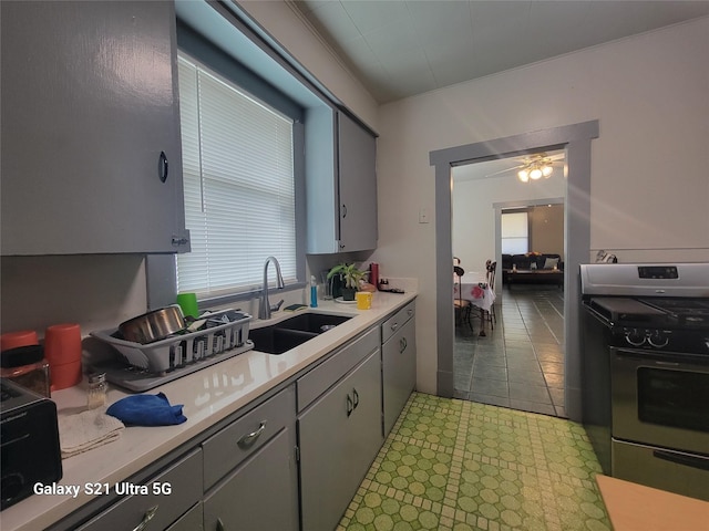 kitchen featuring light countertops, stainless steel gas stove, a sink, and a ceiling fan