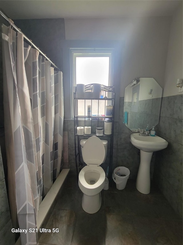 full bathroom featuring tile walls, a wainscoted wall, toilet, curtained shower, and tile patterned flooring