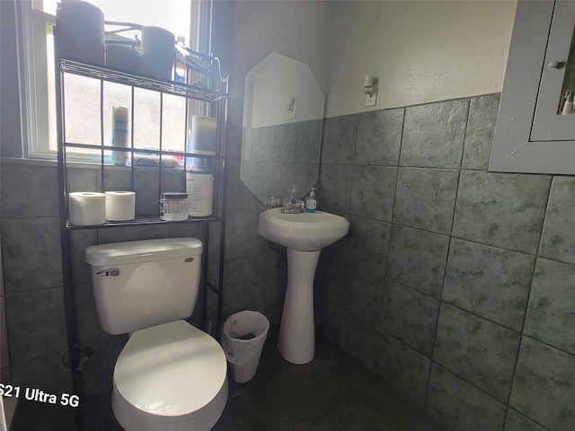 bathroom with electric panel, toilet, and tile walls