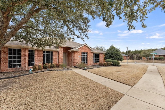 single story home with a front lawn, brick siding, and roof with shingles