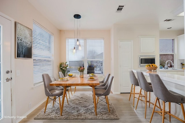 dining space with baseboards, visible vents, and light wood-type flooring