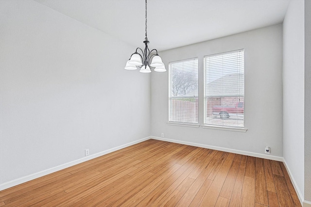 unfurnished room featuring a chandelier, baseboards, and wood finished floors