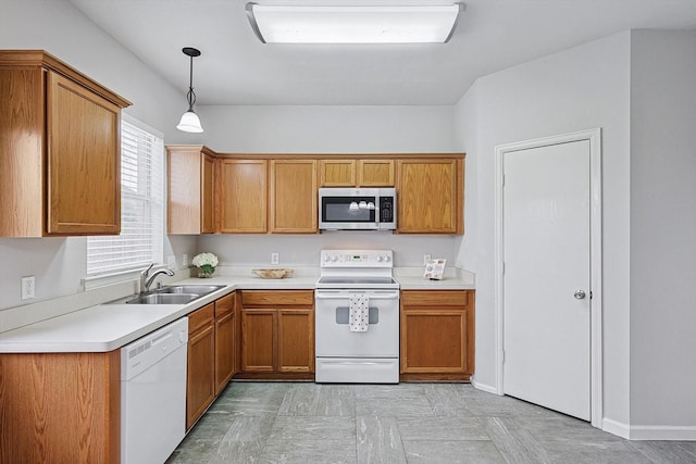 kitchen featuring white appliances, a sink, light countertops, brown cabinetry, and pendant lighting