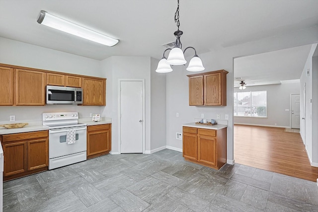 kitchen featuring hanging light fixtures, stainless steel microwave, light countertops, and white electric range oven