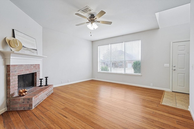 unfurnished living room featuring ceiling fan, light wood-style flooring, a fireplace, visible vents, and baseboards