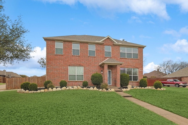 colonial-style house with fence, a front lawn, and brick siding