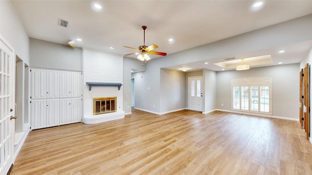 unfurnished living room featuring baseboards, recessed lighting, a brick fireplace, and light wood-style floors