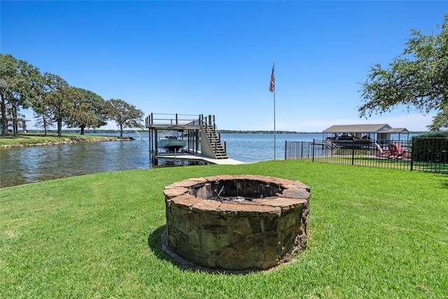 dock area featuring a fire pit, boat lift, stairway, a water view, and a yard