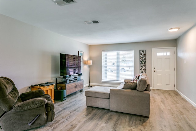 living room with light wood finished floors, baseboards, and visible vents