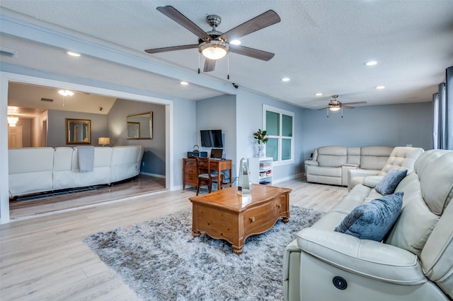 living room featuring recessed lighting, visible vents, light wood-style flooring, a textured ceiling, and baseboards