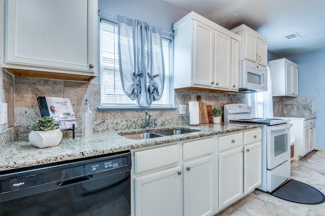 kitchen with white appliances, tasteful backsplash, visible vents, white cabinets, and a sink