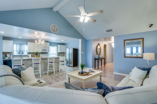 living area with baseboards, visible vents, arched walkways, beamed ceiling, and light wood-style floors