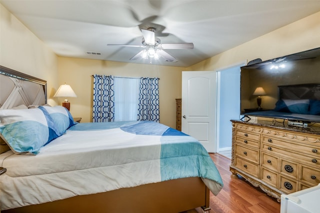 bedroom with a ceiling fan, visible vents, and wood finished floors