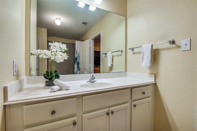 bathroom featuring visible vents, a textured wall, and vanity