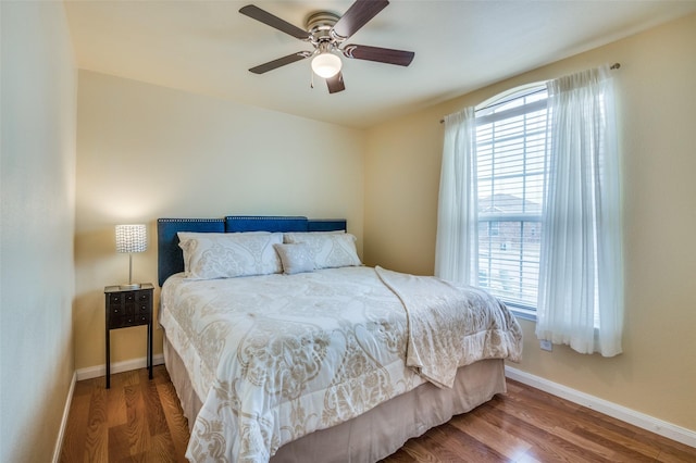 bedroom with ceiling fan, wood finished floors, and baseboards