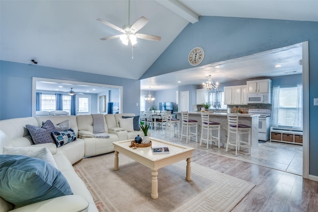 living room with high vaulted ceiling, beamed ceiling, light wood finished floors, and ceiling fan with notable chandelier